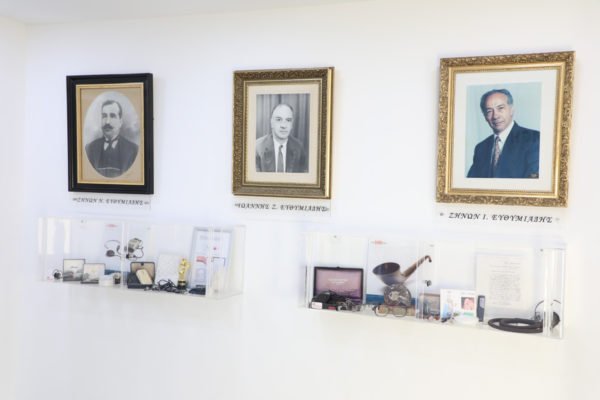 Φωτογραφίες του ιδρυτή και των συνεχιστών πάνω από βιτρίνες με αντικείμενα από την μακρόχρονη ιστορία των Κέντρων.